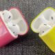 A close-up of unreleased Apple AirPods prototype cases in bright pink and yellow, featuring a glossy plastic finish reminiscent of the iPhone 5c color palette.