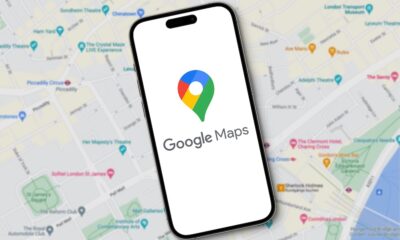 Google Maps logo with lettering is displayed on a smartphone lying on a map view of Google Maps