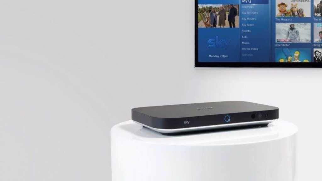 Sky Q box on a white stand with a TV in the background