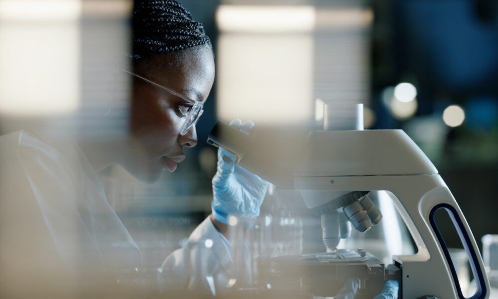 Scientist, microscope and analysis in lab for healthcare and drug discovery