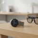 A sleek, modern smartwatch with a minimalist interface sitting on a wooden desk next to a pair of smart glasses, symbolizing the future of Meta's wearable ecosystem.