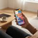 A user holding an iPhone in a modern home setting, reflecting a clean and optimized iOS 26 user experience.