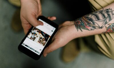 tatooed man holding iphone and scrolling through social media