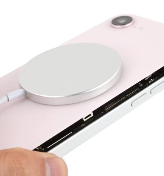 Person holding an iPhone 16e with a soft pink iPhone 17e glass back with a MagSafe charger attached to it.
