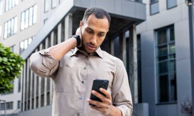 Dunkelhäutiger Mann blickt ratlos auf sein Handy