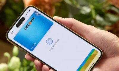 Hand holding iPhone with Discover card shown ready for Apple Pay.