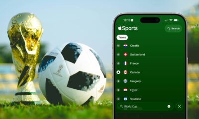 iPhone Showing Apple Sports app with FIFA 2026 World Cup Countries against a FIFA trophy and ball sitting on a field.