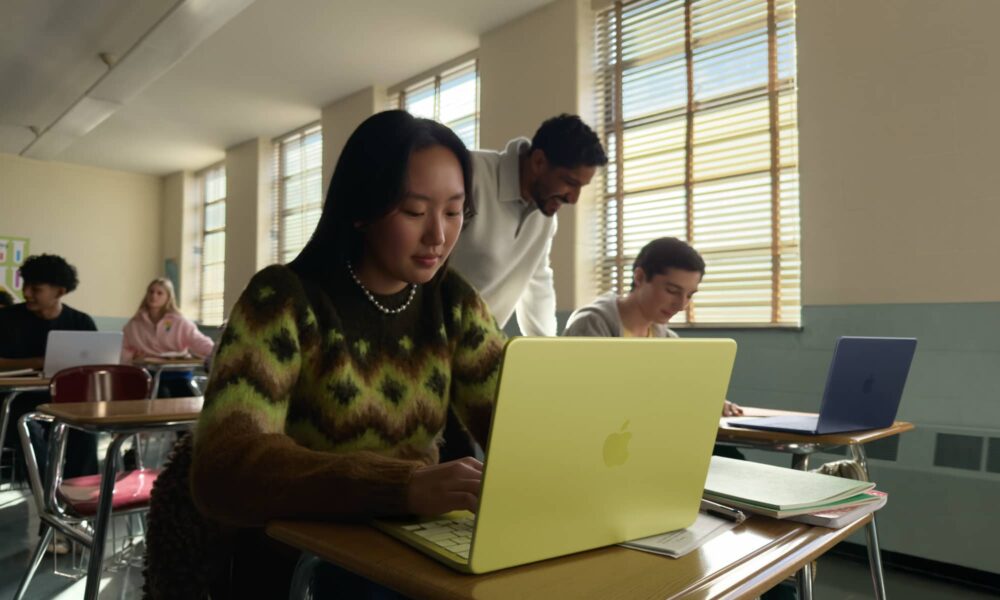 A student working in a bright classroom on a Citrus-colored MacBook Neo, showcasing Apple's most affordable laptop.