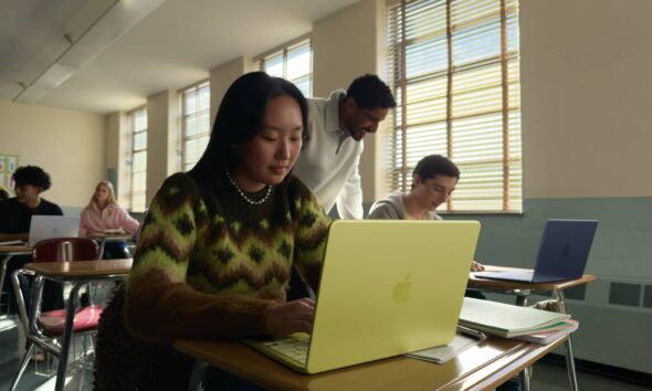 A student working in a bright classroom on a Citrus-colored MacBook Neo, showcasing Apple's most affordable laptop.