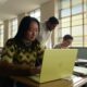 A student working in a bright classroom on a Citrus-colored MacBook Neo, showcasing Apple's most affordable laptop.