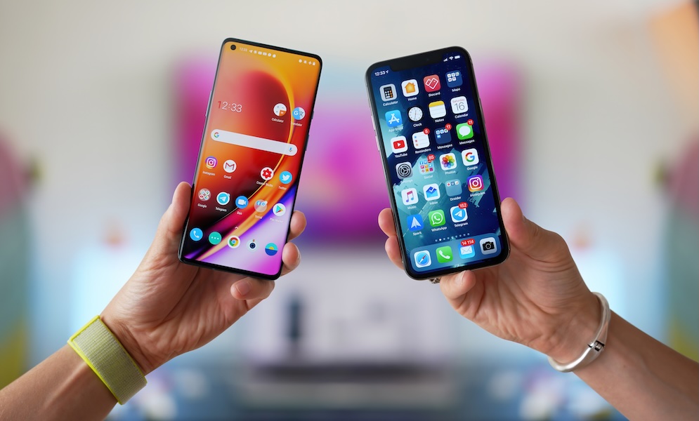 iPhone vs Android. A man holds two smartphones side by side in his hands. Comparison, analysis or comparison of two new smartphones on different operating systems.