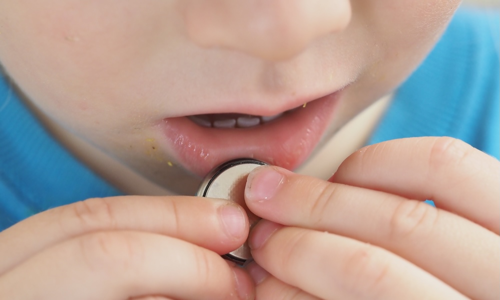 close up coin battery in the child's hands danger of swallowing
