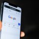 Person holding iPhone with Google search page