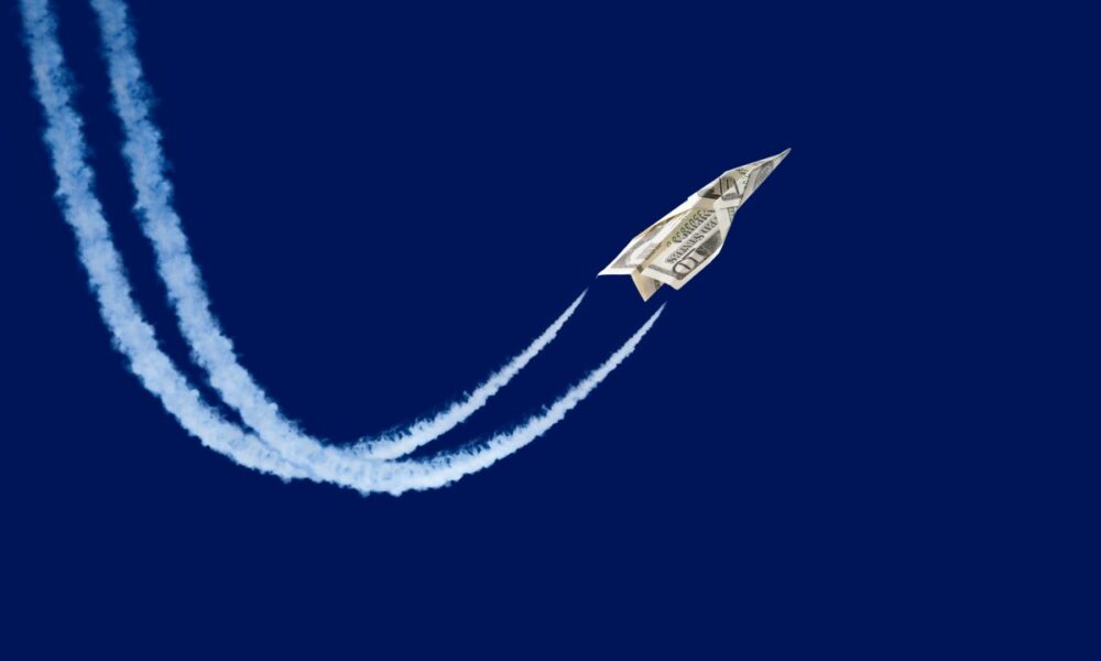 paper plane made from a ten-dollar bill 'flying' with contrails