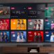 A flat-screen TV displaying the F1 "Race Day Live" multiview feed on the Apple TV app, positioned above a media console in a modern, well-lit living room setting.