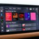 Vehicle infotainment display showing CarPlay Apple Music screen in iOS 27.