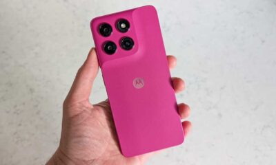A hand holding a pink smartphone, with the rear of the handset facing the camera