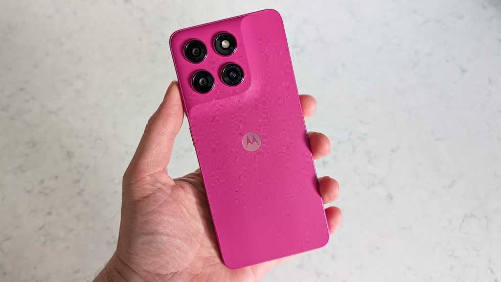 A hand holding a pink smartphone, with the rear of the handset facing the camera