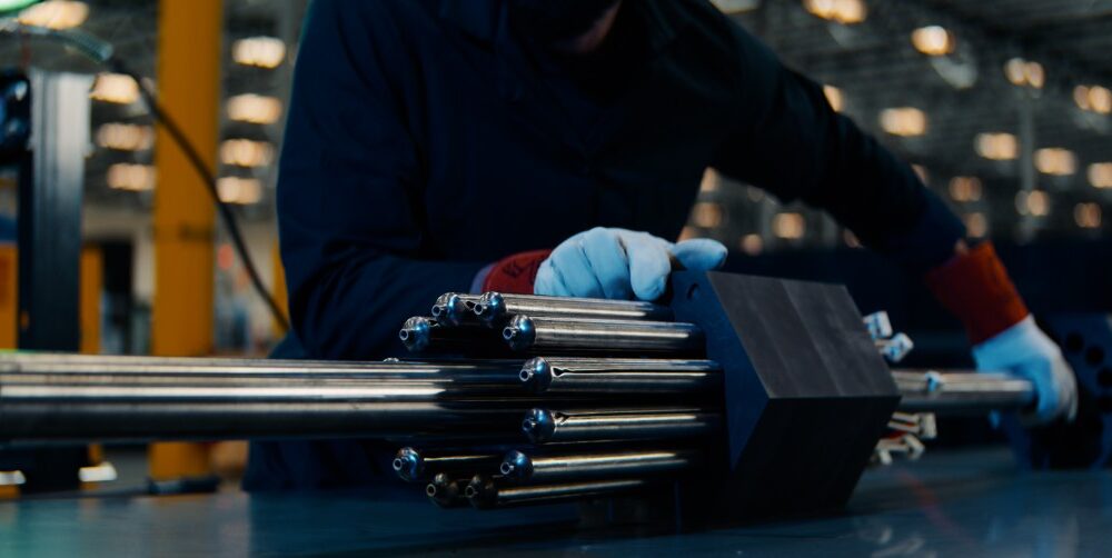 A person handles a nuclear fuel assembly.