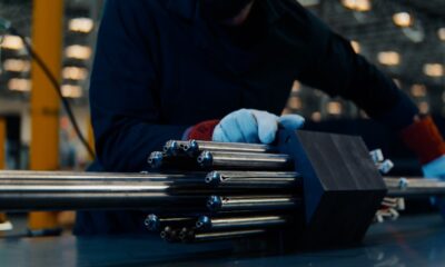 A person handles a nuclear fuel assembly.