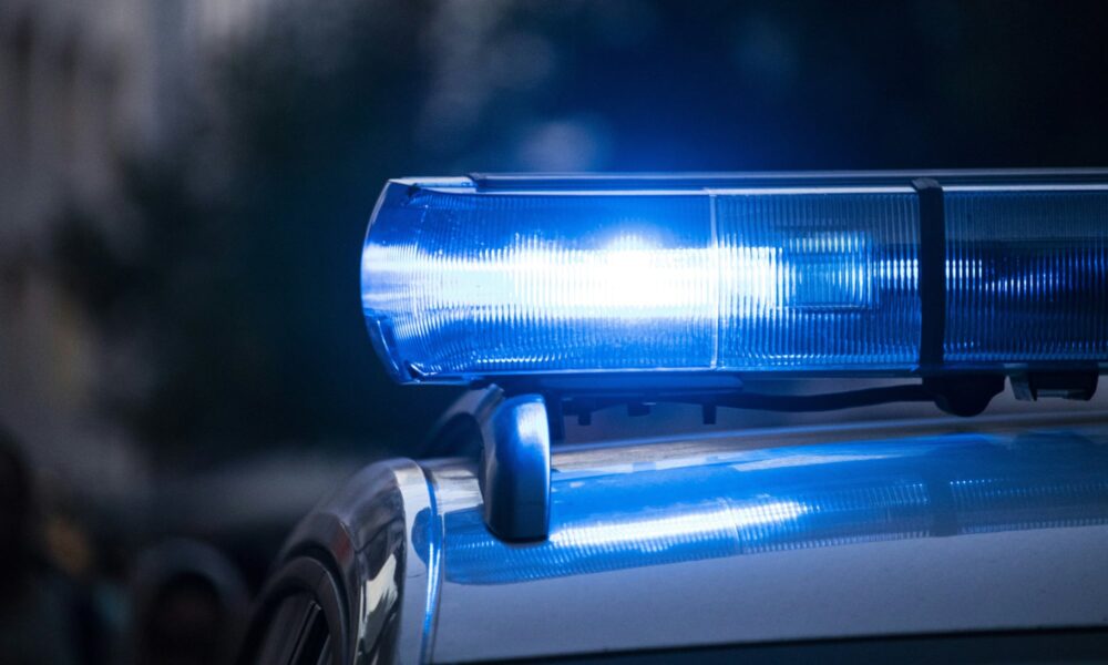Selective focus of flashing blue police lights on a vehicle roof with a soft bokeh city background.