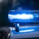 Selective focus of flashing blue police lights on a vehicle roof with a soft bokeh city background.