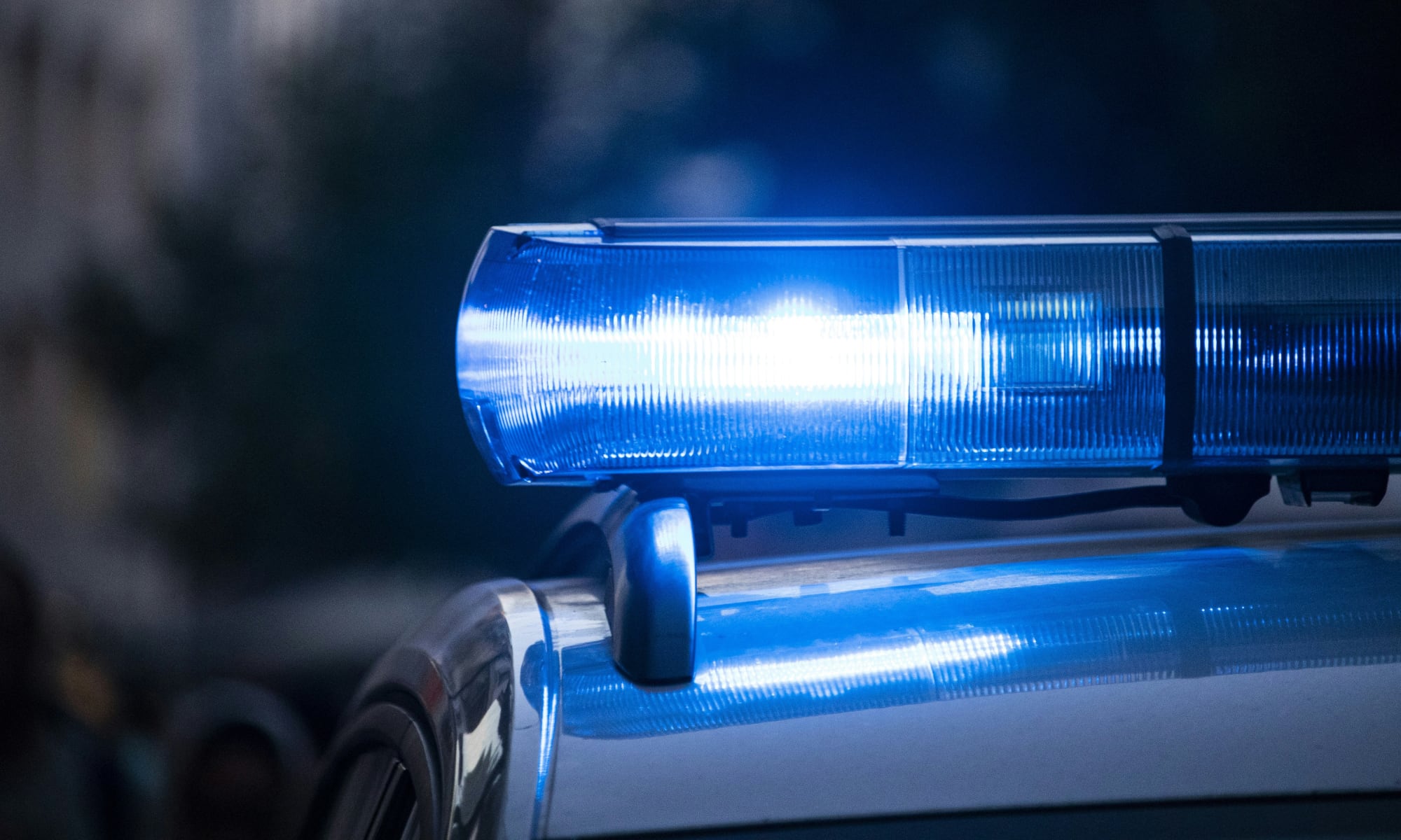 Selective focus of flashing blue police lights on a vehicle roof with a soft bokeh city background.