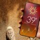 Someone using a smartphone displaying hot weather