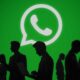 Whatsapp Logo vor grünem Hintergrund, davor Menschen mit Handys