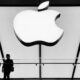 two people silhoutted in front of large Apple logo