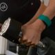 Woman wearing green Whoop fitness band while lifting weights.
