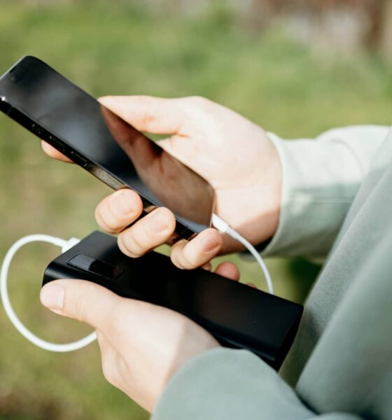 person holding iPhone and battery pack
