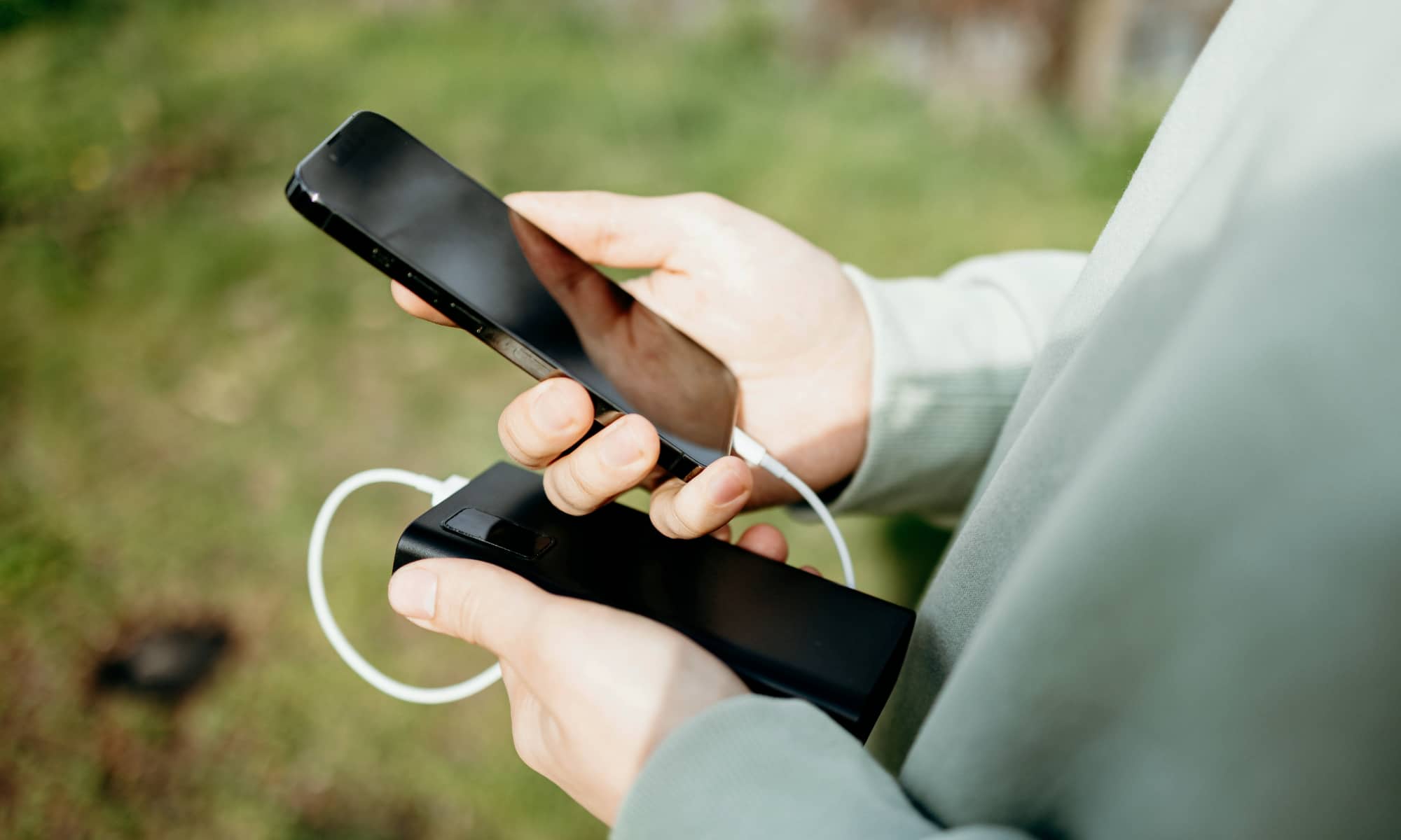 person holding iPhone and battery pack